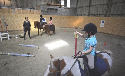 Jeux à dos de poney dans un manège dédié aux tout petits.